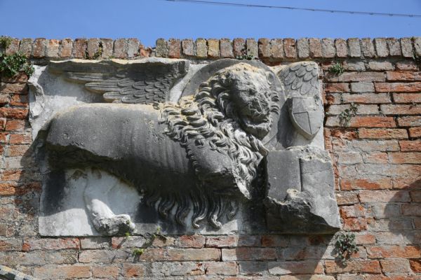 Lion of St. Mark with the coat of arms of the House of Calbo, 15th century (?) – Exterior on the back wall between the Archives building and the Council building, Torcello Island, Venice