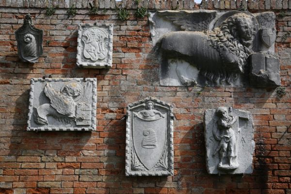 Exterior on the back wall between the Palazzo dell'Archivio and the Palazzo del Consiglio. Coats of arms of Venetian families, Marcian lions and Sant'Andrea - Torcello Museum, Venice